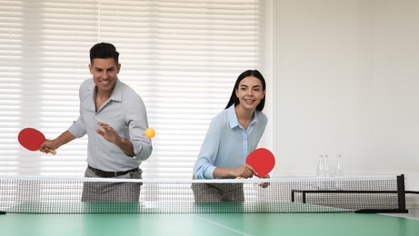 Business people playing ping pong in office