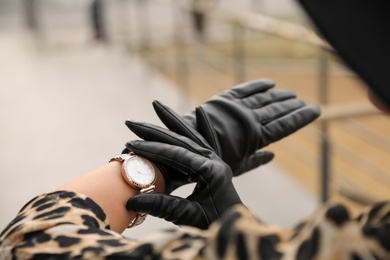 Young woman in stylish black leather gloves outdoors, closeup