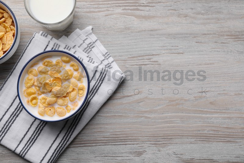 Tasty cornflakes with milk served on wooden table, flat lay. Space for text