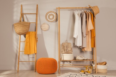 Modern dressing room interior with stylish clothes, shoes and orange pouf