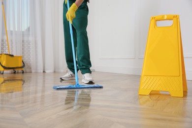 Professional janitor cleaning parquet floor with mop indoors, closeup