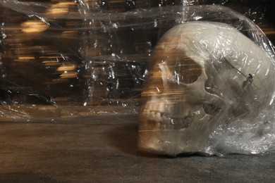 Photo of Human skull with stretch film on stone surface against black background. Space for text