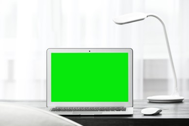 Image of Laptop display with chroma key on desk in room. Comfortable workplace with modern computer