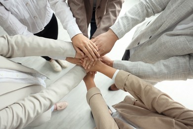 Group of people holding hands together indoors, above view. Unity concept