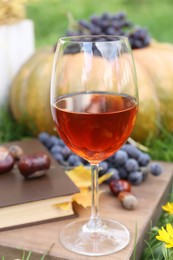 Glass of wine on wooden board outdoors. Autumn picnic