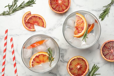Delicious refreshing drink with sicilian orange and rosemary on white marble table, flat lay