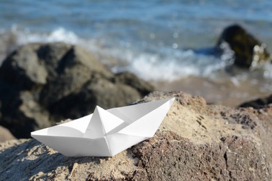 White paper boat on rock near sea, space for text