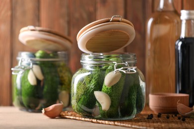 Photo of Glass jars with fresh cucumbers and other ingredients on wooden table. Canning vegetable