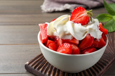 Delicious strawberries with whipped cream served on wooden table, closeup