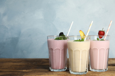 Different tasty milk shakes on wooden table. Space for text
