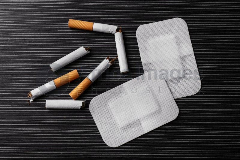 Nicotine patches and broken cigarettes on black table, flat lay