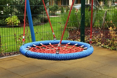 Photo of Light blue nest swing on outdoor playground in residential area