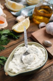 Tasty tartar sauce and ingredients on wooden table