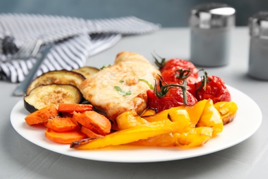 Photo of Delicious cooked chicken and vegetables on grey table, closeup. Healthy meals from air fryer
