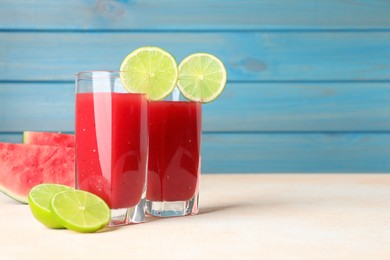 Photo of Tasty summer watermelon drink with lime in glasses on table against light blue background. Space for text