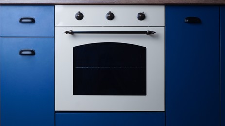 Photo of New stylish closed oven in kitchen. Cooking appliance