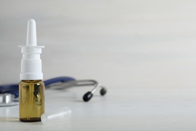 Bottle of nasal spray on white wooden table. Space for text