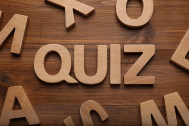 Word Quiz made with letters on wooden table, flat lay