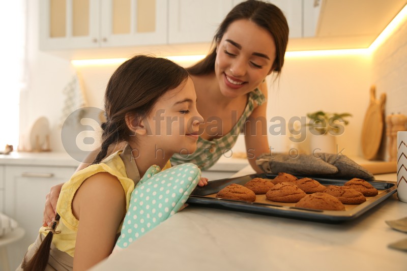 Mother and daughter with freshly baked cookies in kitchen