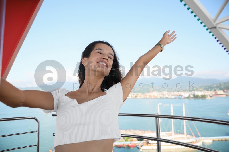 Portrait of emotional young woman on Ferris wheel near sea