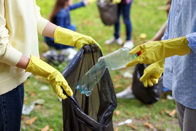 Photo of Women with plastic bag collecting garbage in park, closeup