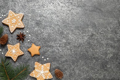 Tasty Christmas cookies, fir branches, cones and anise on grey table, flat lay. Space for text