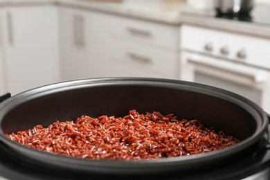 Modern multi cooker with boiled brown rice in kitchen, closeup. Space for text