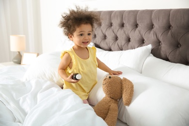 Cute African American child imagining herself as doctor while playing with toy bunny at home