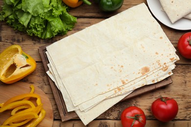 Photo of Delicious Armenian lavash and fresh vegetables on wooden table, flat lay