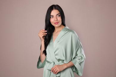 Pretty young woman in light silk robe on beige background