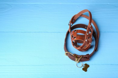 Photo of Brown leather dog muzzle and collar on light blue wooden table, space for text