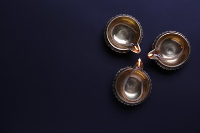Lit diyas on dark background, flat lay with space for text. Diwali lamps