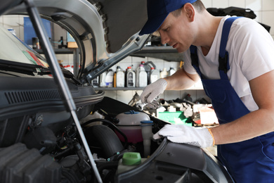 Photo of Professional auto mechanic fixing modern car in service center