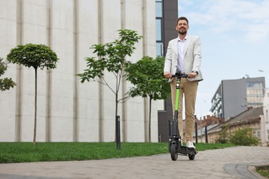 Businessman riding modern kick scooter on city street, space for text