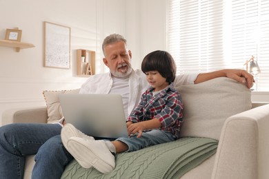 Grandfather and grandson using laptop together at home