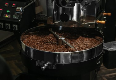 Photo of Modern coffee roaster machine with beans indoors