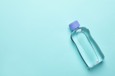 Bottle of baby oil on turquoise background, top view. Space for text