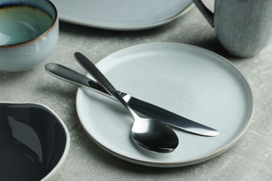 Stylish empty dishware and cutlery on light grey table, closeup