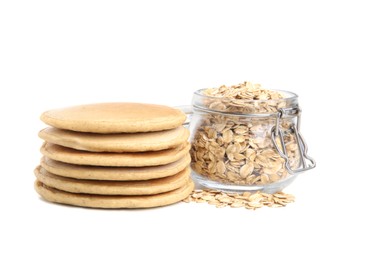 Tasty oatmeal pancakes and flakes on white background