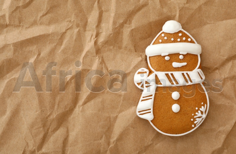 Christmas snowman shaped gingerbread cookie on crumpled parchment, top view. Space for text
