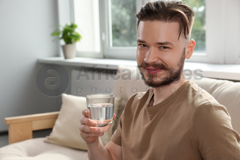 Handsome man with glass of water at home. Refreshing drink