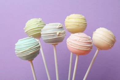Sweet colorful cake pops on purple background
