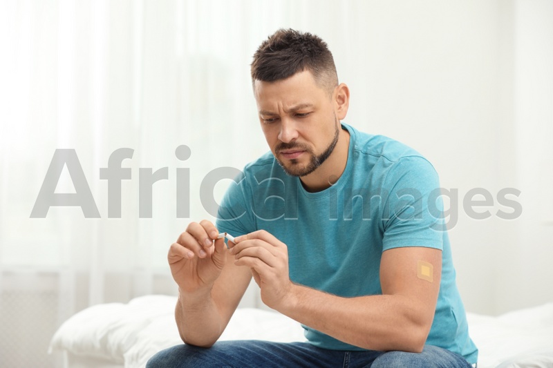 Man with nicotine patch and cigarette in bedroom