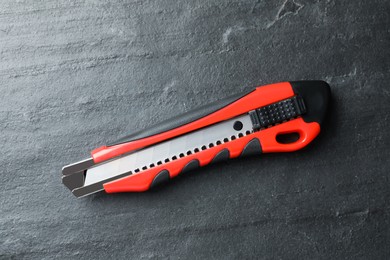 Utility knife on black table, top view. Construction tool