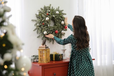 Young woman decorating Christmas wreath at home