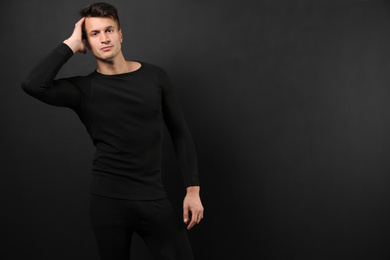 Man wearing thermal underwear on black background. Space for text