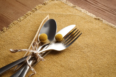 Set of cutlery, yellow cloth and autumnal decor on wooden background. Table setting elements