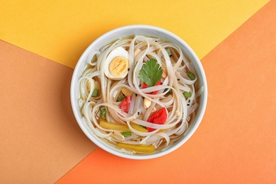 Photo of Tasty ramen with rice noodles and vegetables on color background, top view