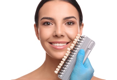 Doctor checking young woman's teeth color on white background. Cosmetic dentistry