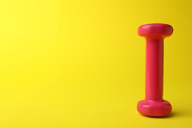 Stylish dumbbell on yellow background, space for text